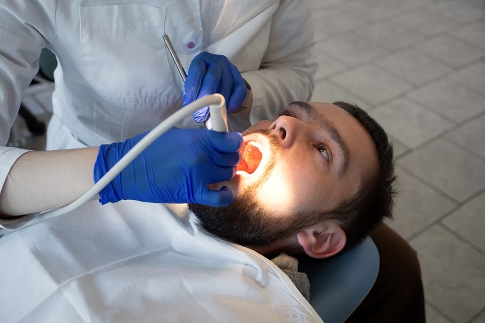 Patient undergoing dental treatment with a laser tool — Dentist in San Mateo A dentist using a laser tool on a patient’s open mouth for treatment during a dental appointment in San Mateo — Dentist in San Mateo