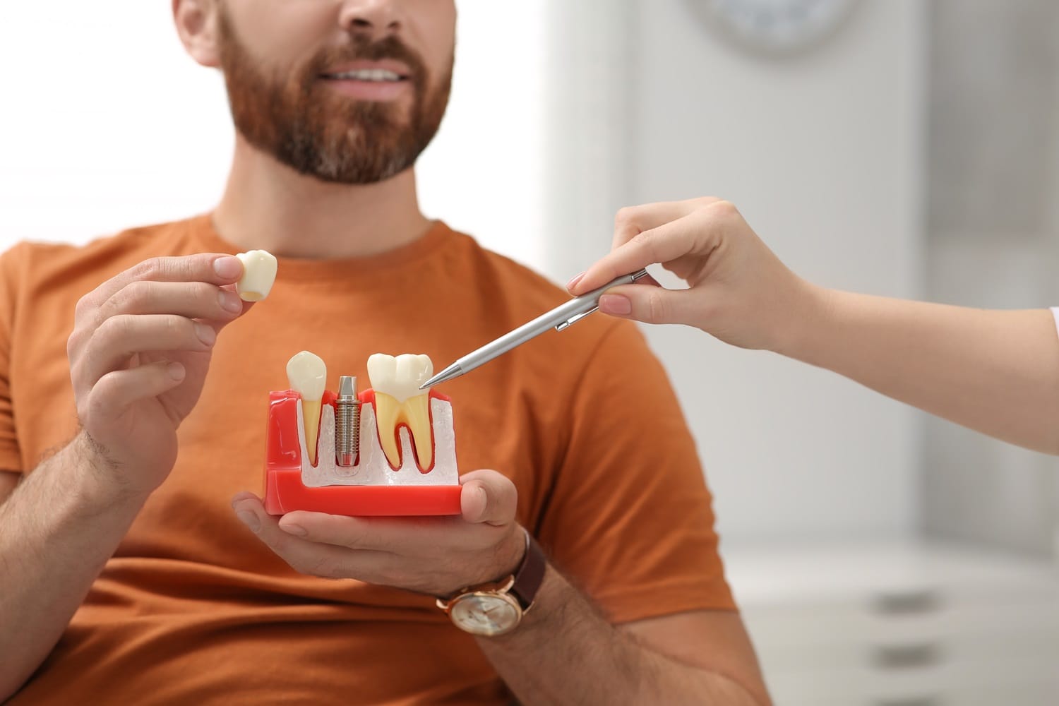 patient holding human teeth model - Dental Implants in San Mateo