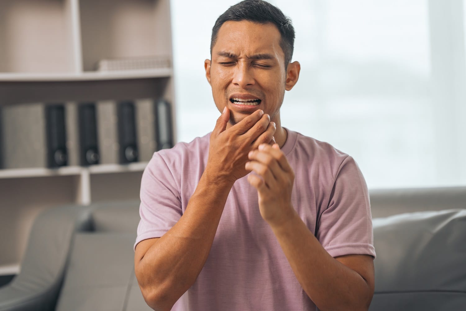 Man with Tooth Pain — Emergency Dentist San Mateo Man experiencing severe tooth pain while holding his jaw, representing a patient in need of emergency dental care in San Mateo - Emergency Dentist San Mateo