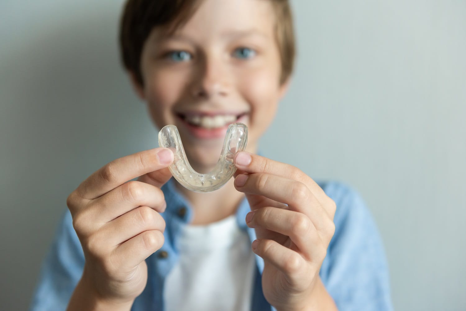 Smiling child showing a clear dental mouthguard – Pediatric Dentist San Mateo