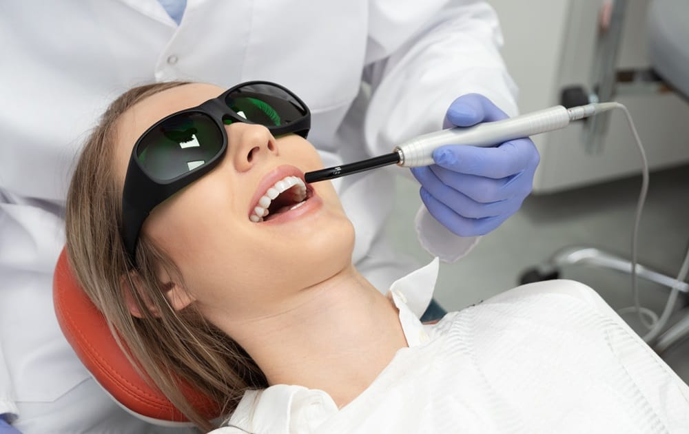 Laser Teeth Whitening Treatment – Dentist in San Mateo Patient receiving laser teeth whitening treatment while wearing protective glasses — Dentist in San Mateo.