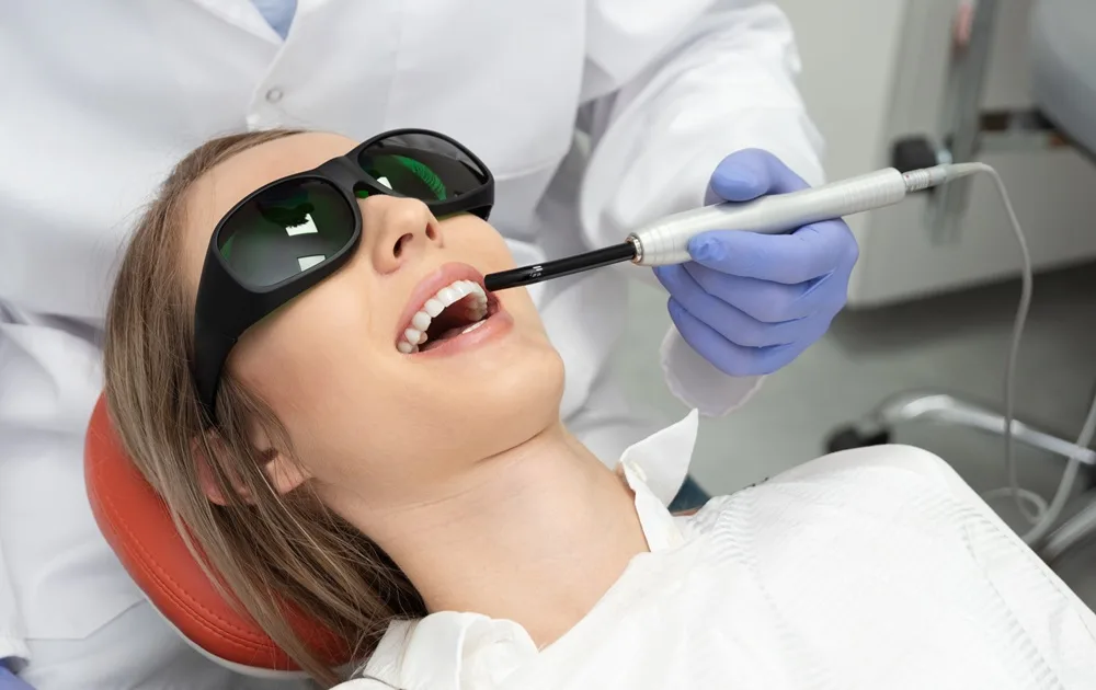 Laser Teeth Whitening Treatment – Dentist in San Mateo Patient receiving laser teeth whitening treatment while wearing protective glasses — Dentist in San Mateo.