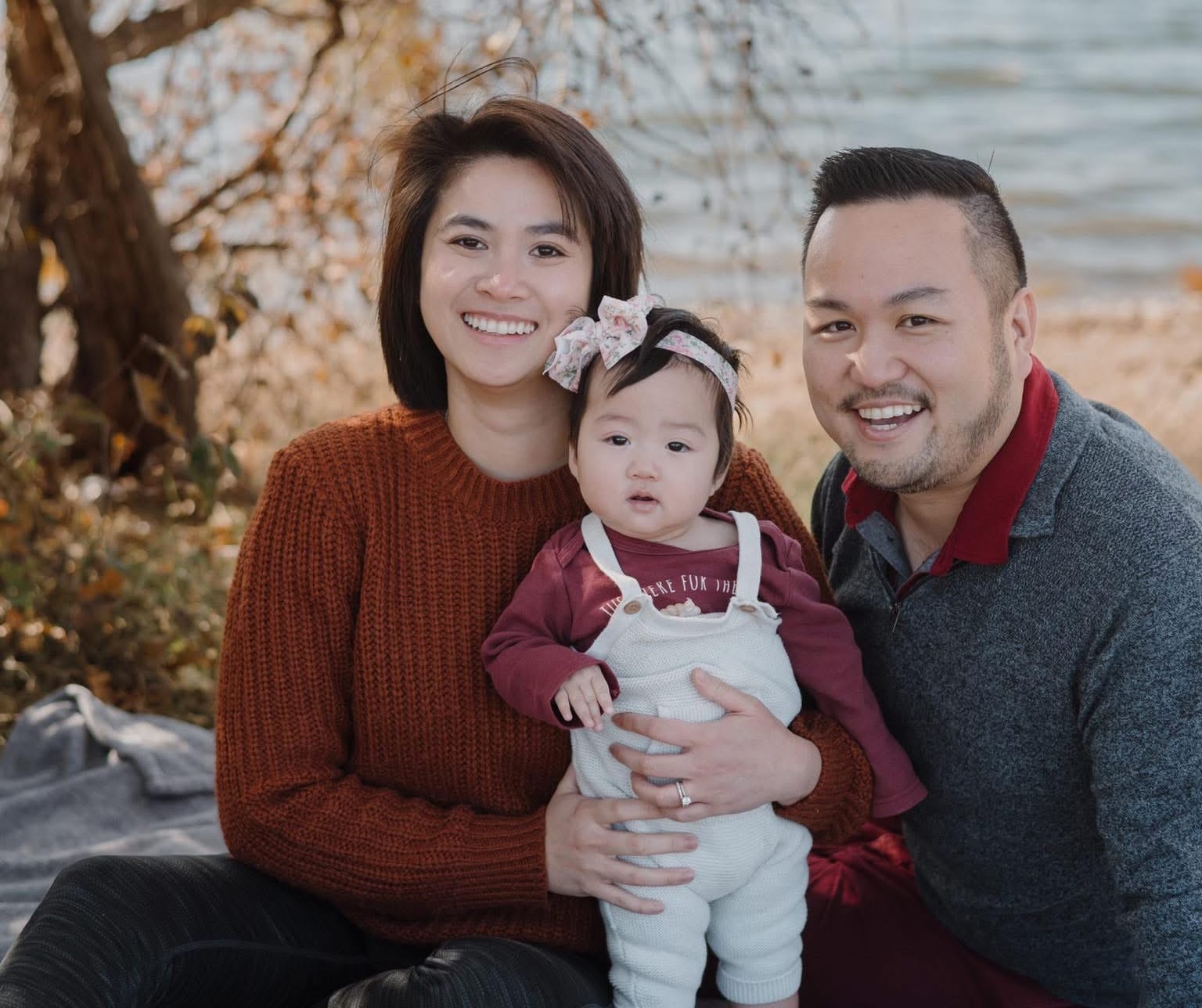 Dr. Taw and his family - Dentist in San Mateo Happy family sitting together outdoors near the water, smiling for a photo — representing healthy, confident smiles supported by a family - dentist in San Mateo.
